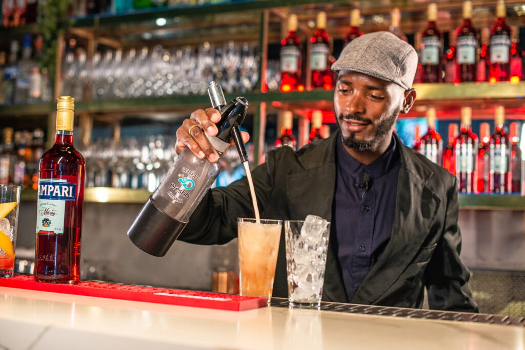 Bartender Pretinho Cereja utilizando tônica Preshh com Campari